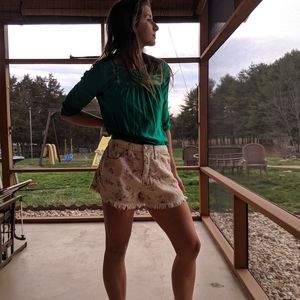 White and pink flowered frayed jean shorts.